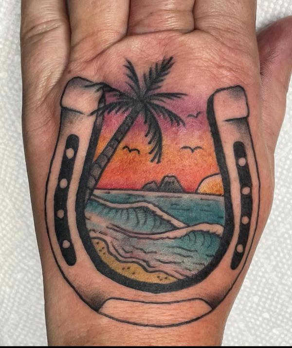 Horseshoe and palm tree hand tattoo
