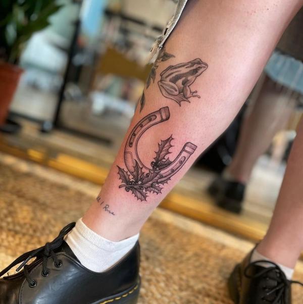 Horseshoe with holly lower leg tattoo