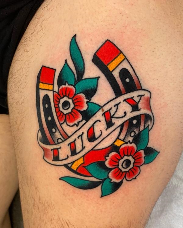 Lucky horseshoe with flower thigh tattoo