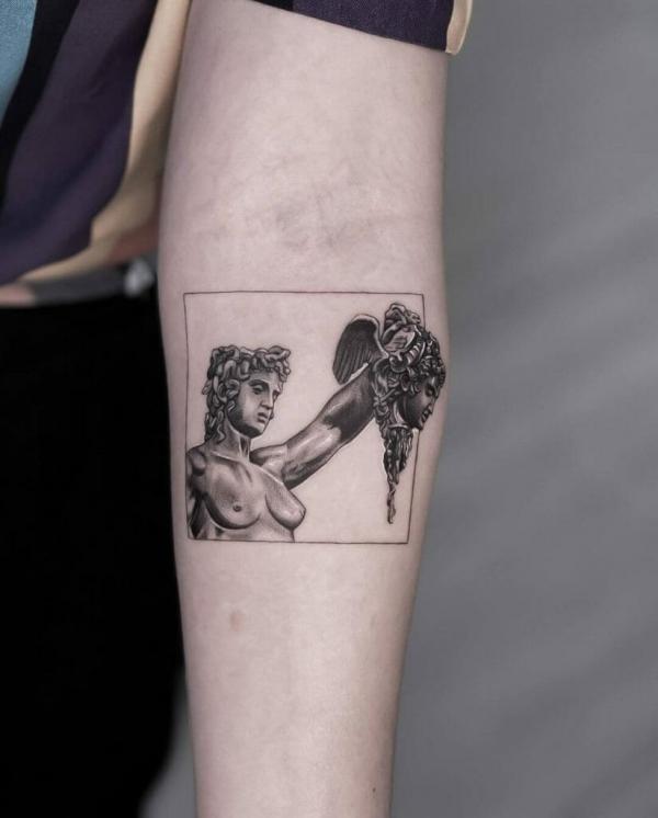 Perseus holding Medusa head tattoo below inner elbow
