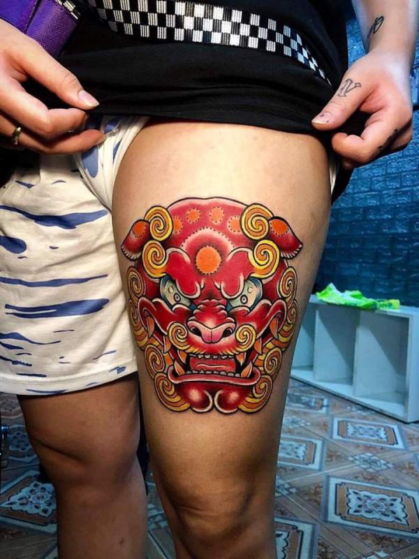Red and yellow foo dog tattoo above knee
