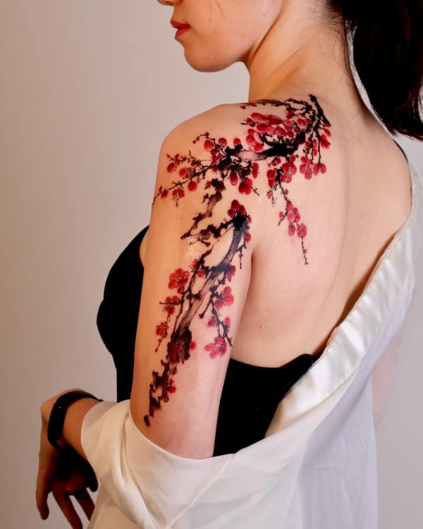 Red plum blossom back of arm tattoo