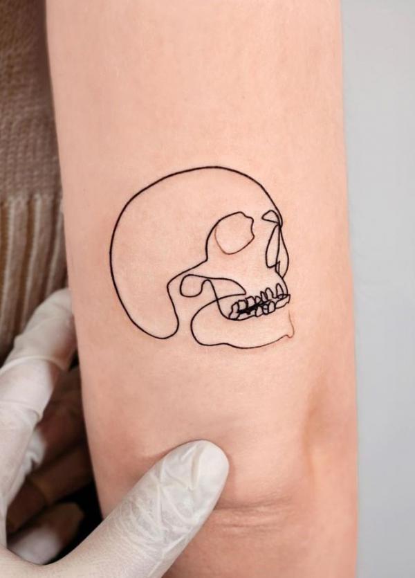 Skull outline tattoo above elbow