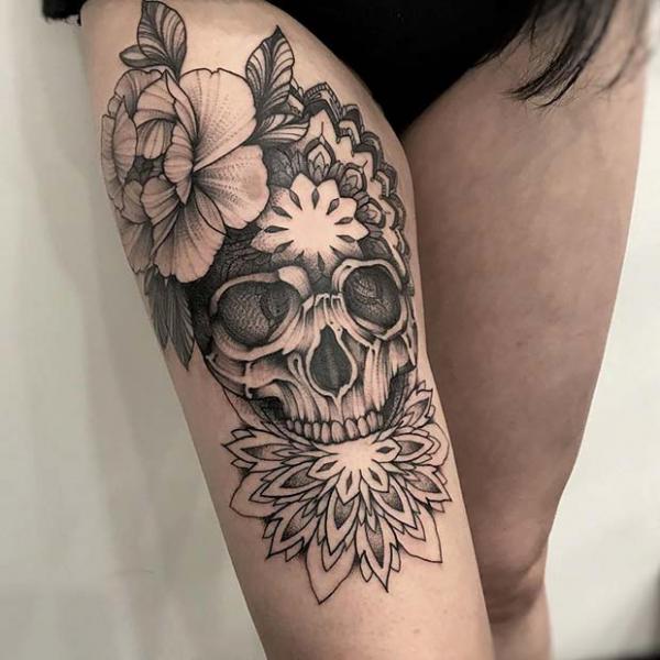 Skull with flowers above knee tattoo