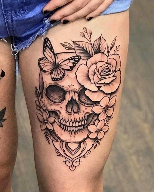 Skull with rose and butterfly above knee tattoo