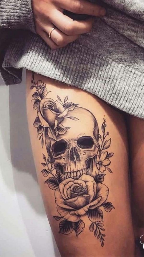 Skull with roses above knee tattoo