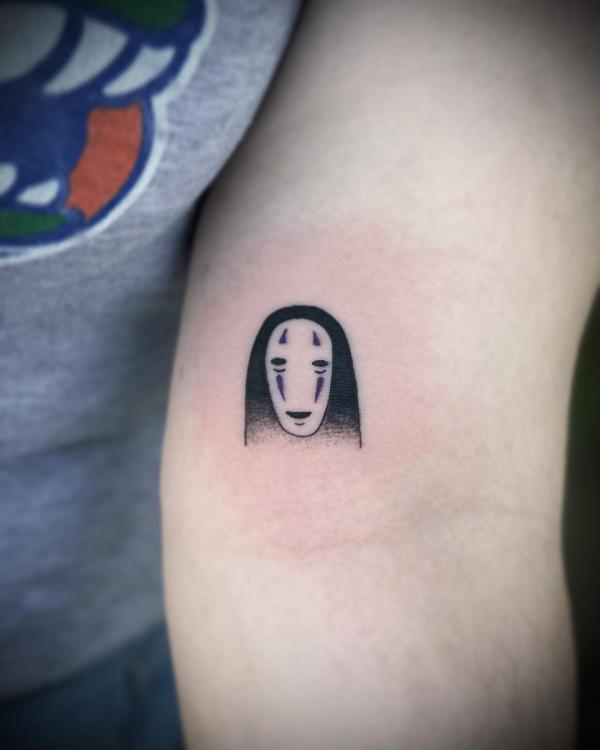 Small No Face tattoo above inner elbow