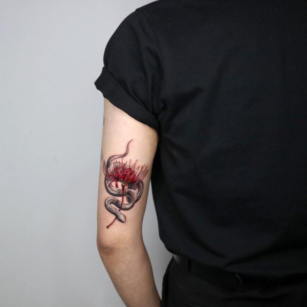 Snake and spider lily back of arm tattoo