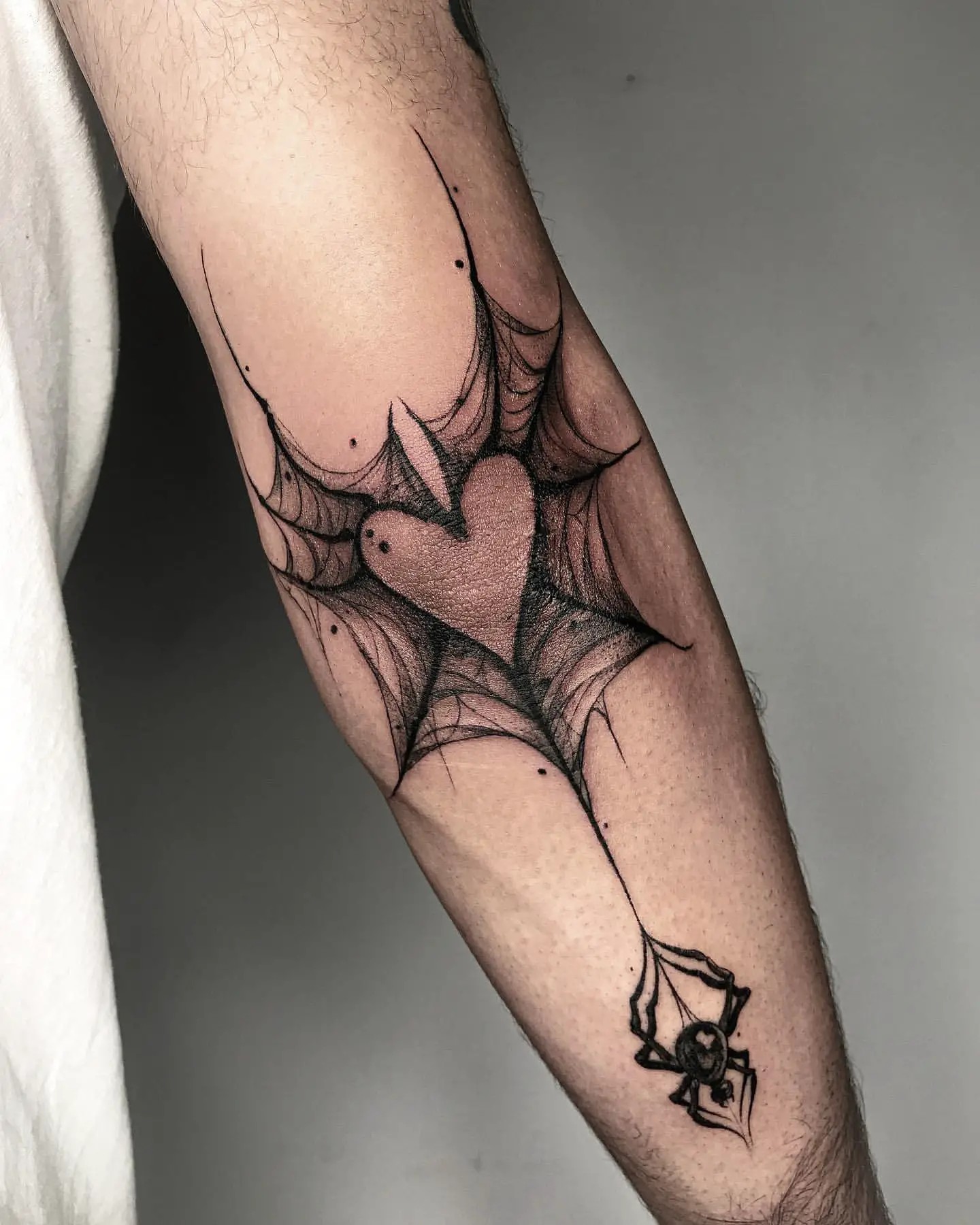 Spiderweb with central heart tattoo on elbow
