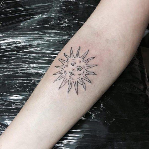 Sun face below elbow tattoo