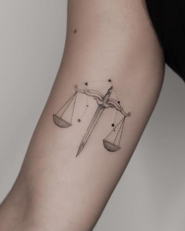 Sword Libra and constellation upper arm tattoo