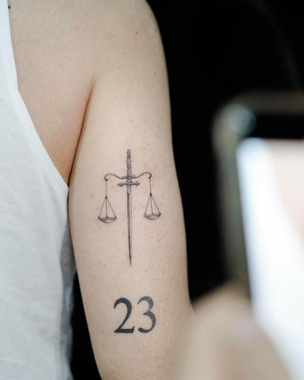 Sword libra with number 23 back of arm tattoo