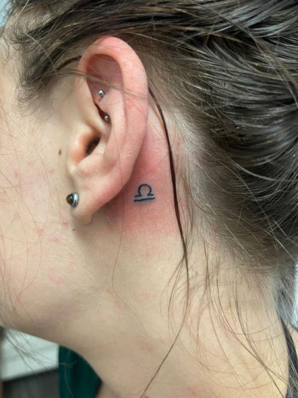 Tiny libra sign tattoo behind ear