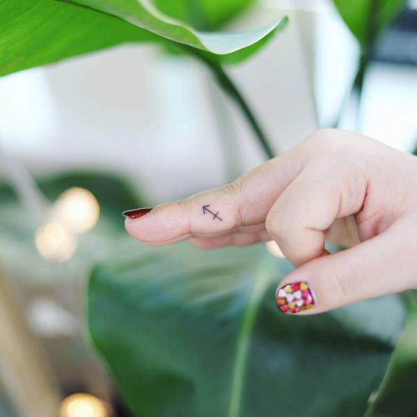 Tiny sagittarius glyph finger tattoo