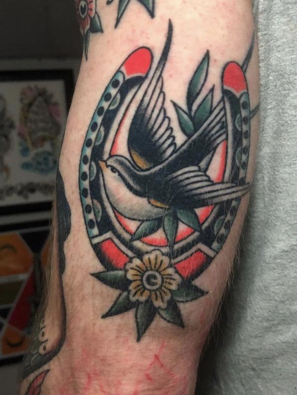 Traditional horseshoe and swallow back of arm tattoo