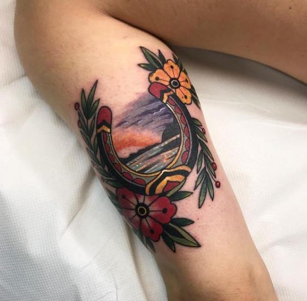 Traditional horseshoe with flower fern and sunset tattoo