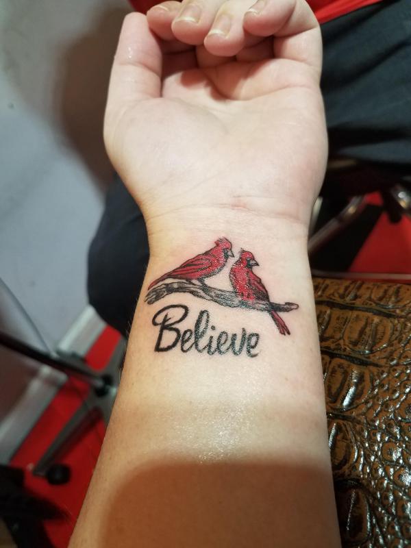 Two cardinal wrist tattoo with word Believe