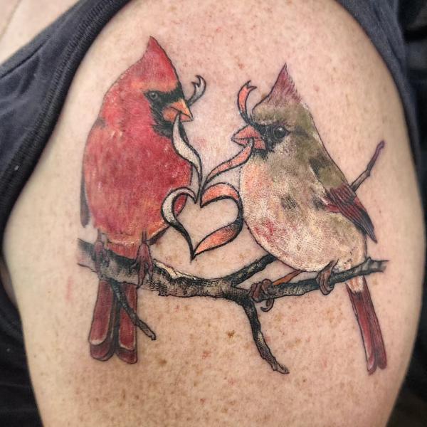 Two cardinals holding ribbon in the shape of heart tattoo