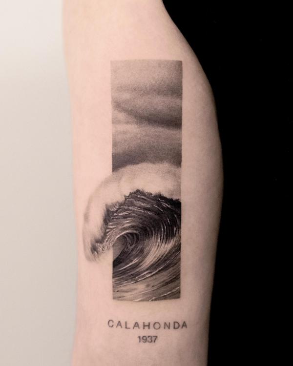 Wave with name Calahonda back of arm tattoo