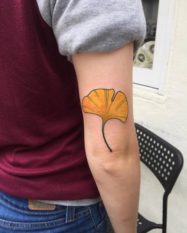 Yellow ginkgo leaf tattoo above elbow