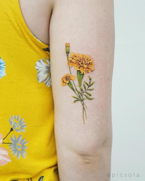 Yellow marigold back of arm tattoo
