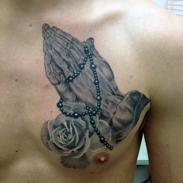 praying hands with catholic rosary mens upper chest tattoo