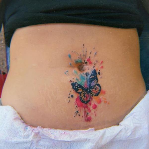 A butterfly on watercolor backdrop tummy tattoo
