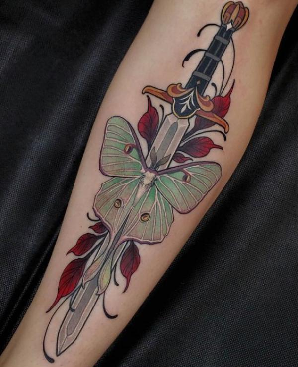 A dagger through luna moth forearm tattoo