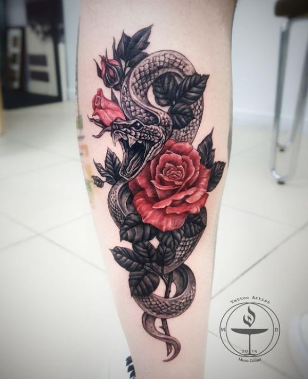 A snake interwined with rose and bud tattoo on calf