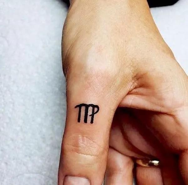 A tiny Virgo gluph thumb finger tattoo
