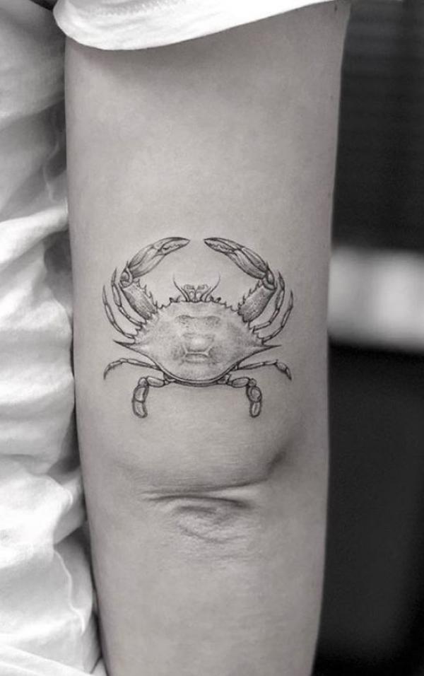Black and grey Zodiac cancer tattoo above elbow