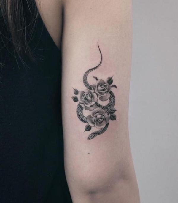 Black and grey snake with three roses tattoo above elbow