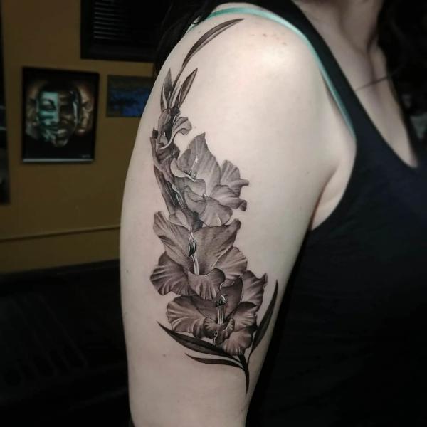 Black and white gladiolus upper arm tattoo