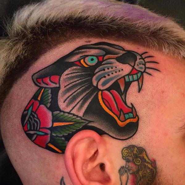 Bold traditional panther head tattoo above the ear