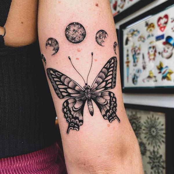 Butterfly and moon cycle upper arm tattoo