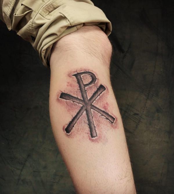 Carved Chi Rho leg tattoo