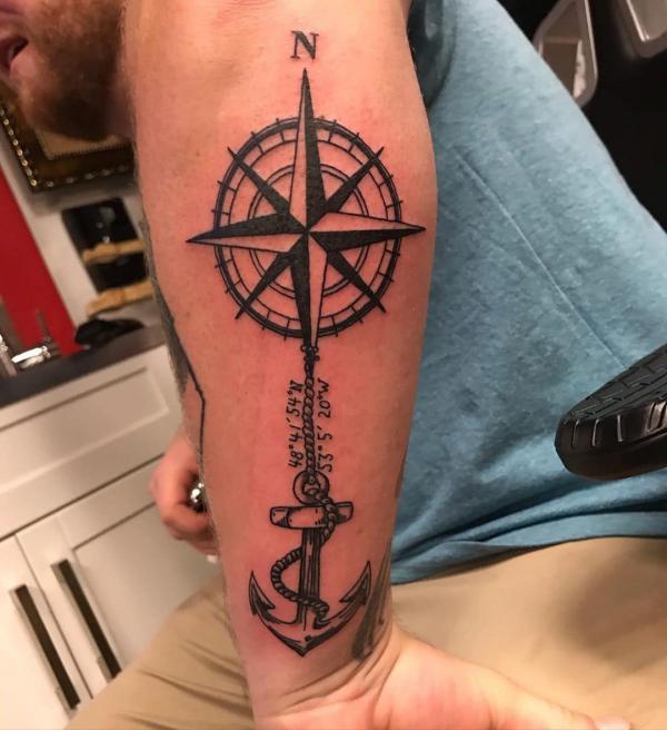 Compass and anchor with coordinates tattoo on outer forearm