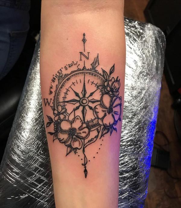 Compass with coordinates and flowers tattoo on forearm