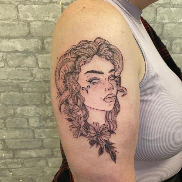 Female with Aries Ram horns glyph and daisy tattoo
