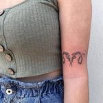 Floral vine aries tattoo above inner elbow