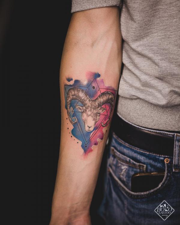 Geometric Aries Ram tattoo on watercolor backdrop