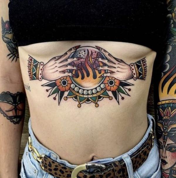 Hands with firing crystal ball stomach tattoo