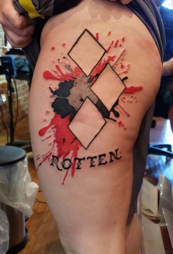 Harley Quinn diamond on watercolor backdrop thigh tattoo