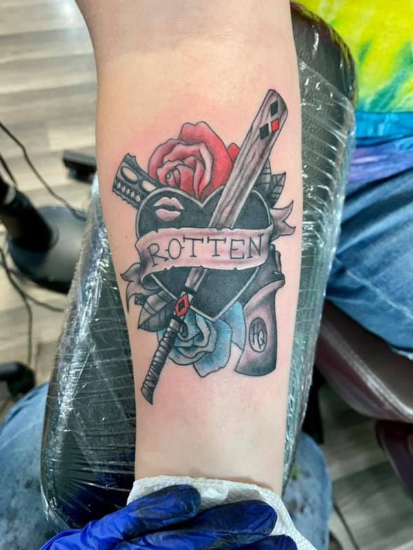 Heart and gun with rose and Harley Quinns baseball bat wrapped with ribbon bearing the word Rotten tattoo
