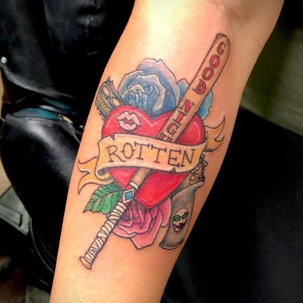 Heart with roses and Harley Quinns Good Night baseball bat wrapped with ribbon bearing the word Rotten tattoo on forearm