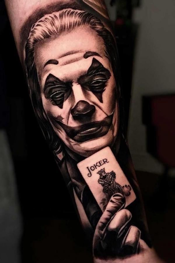 Joaquin Phoenix joker with a card forearm tattoo