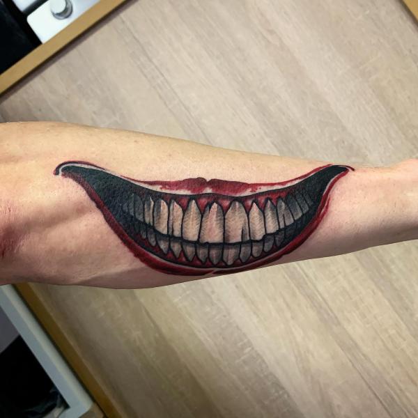 Joker smile teeth forearm tattoo