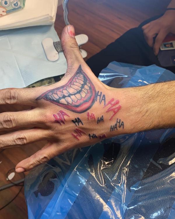 Joker smile with words hahaha hand tattoo