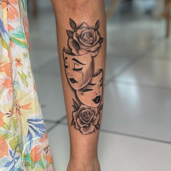 Laugh now cry later masks with roses tattoo on forearm