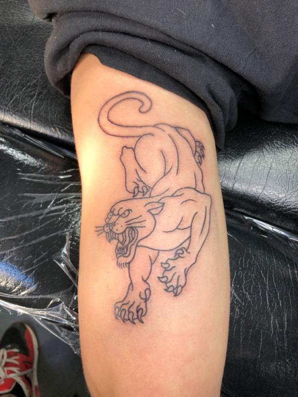 Prowling panther outline back of arm tattoo